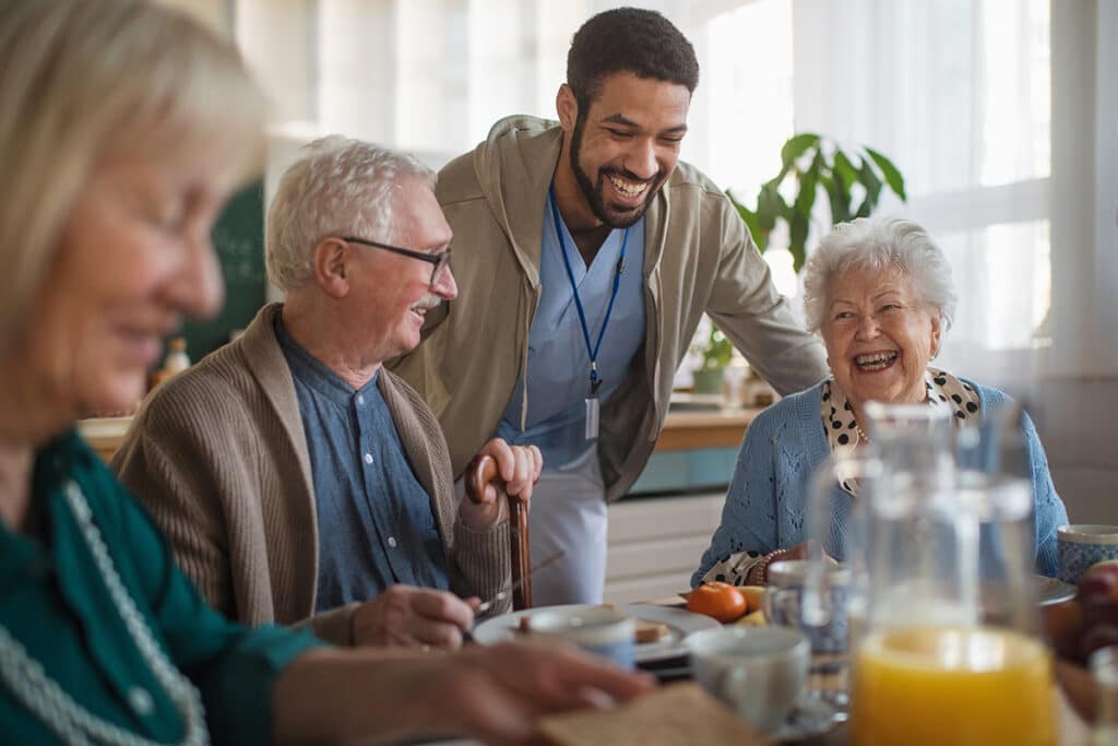Group of cheerful seniors enjoying breakfast in nursing home care center.